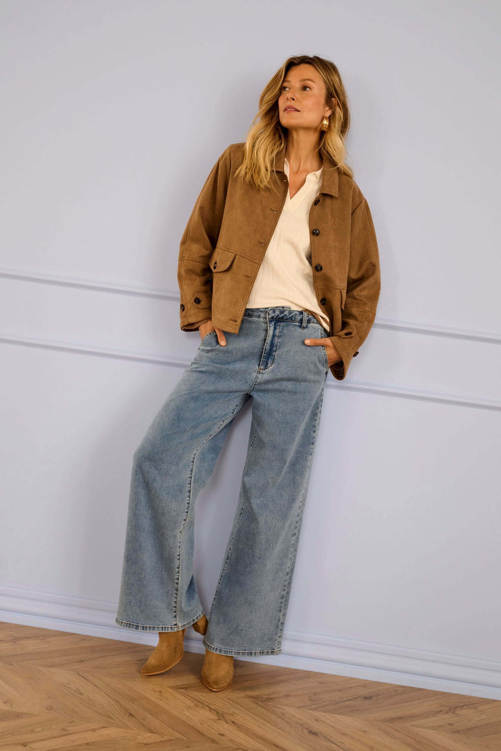 Femme portant un Polo Villea en maille avec veste marron et jean large, style moderne et élégant. Mode raffiné et féminin.