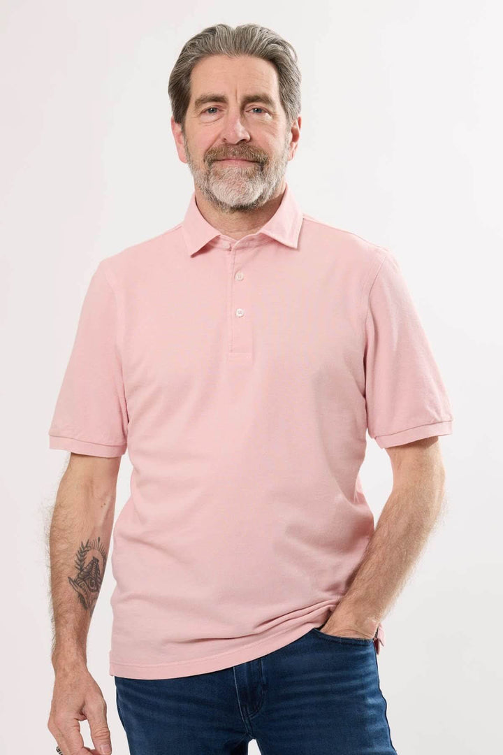 Homme portant un polo classique en coton rose, col en maille piquée, manches courtes, style décontracté.
