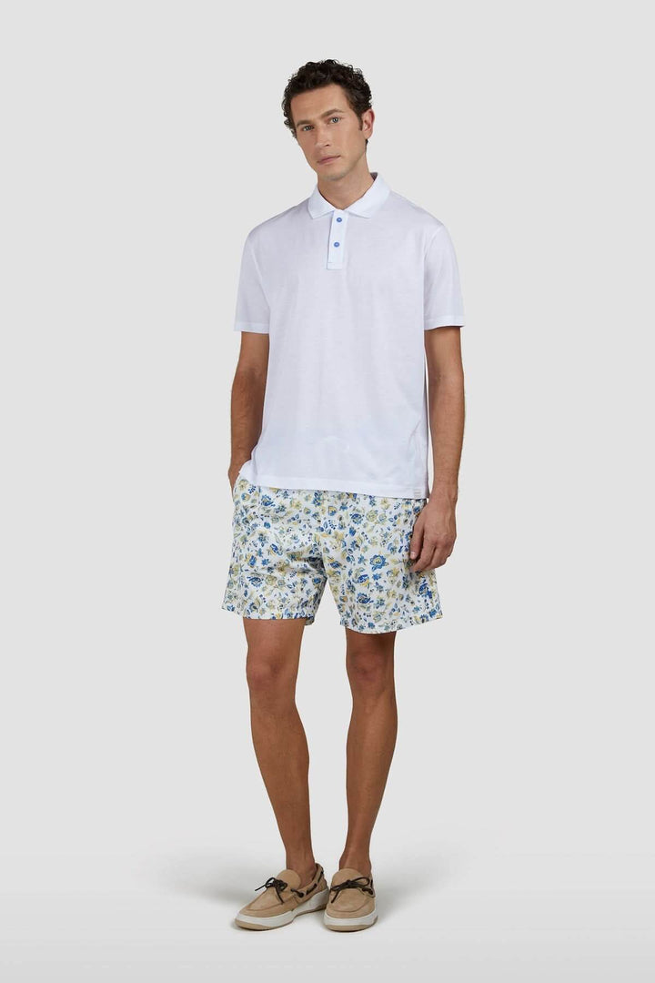 Homme portant un polo en coton léger avec col contrasté et short imprimé fleuri pour un look estival sophistiqué.