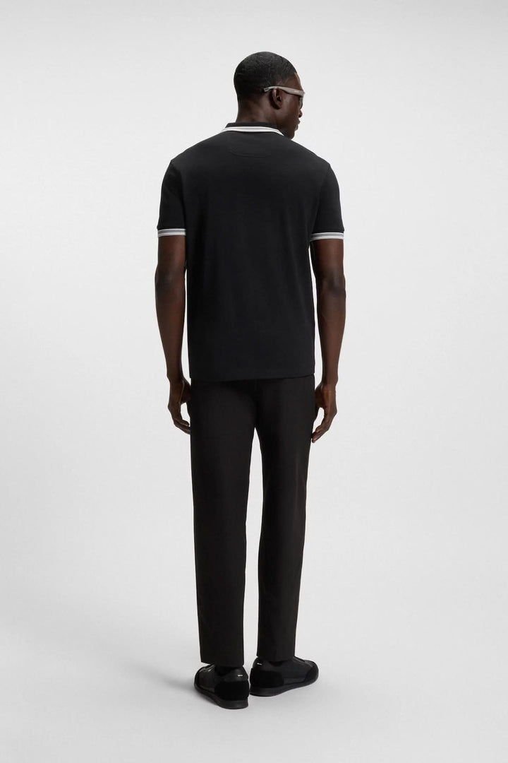 Homme portant un polo minimaliste noir avec col contrastant et pantalon noir, vue de dos.
