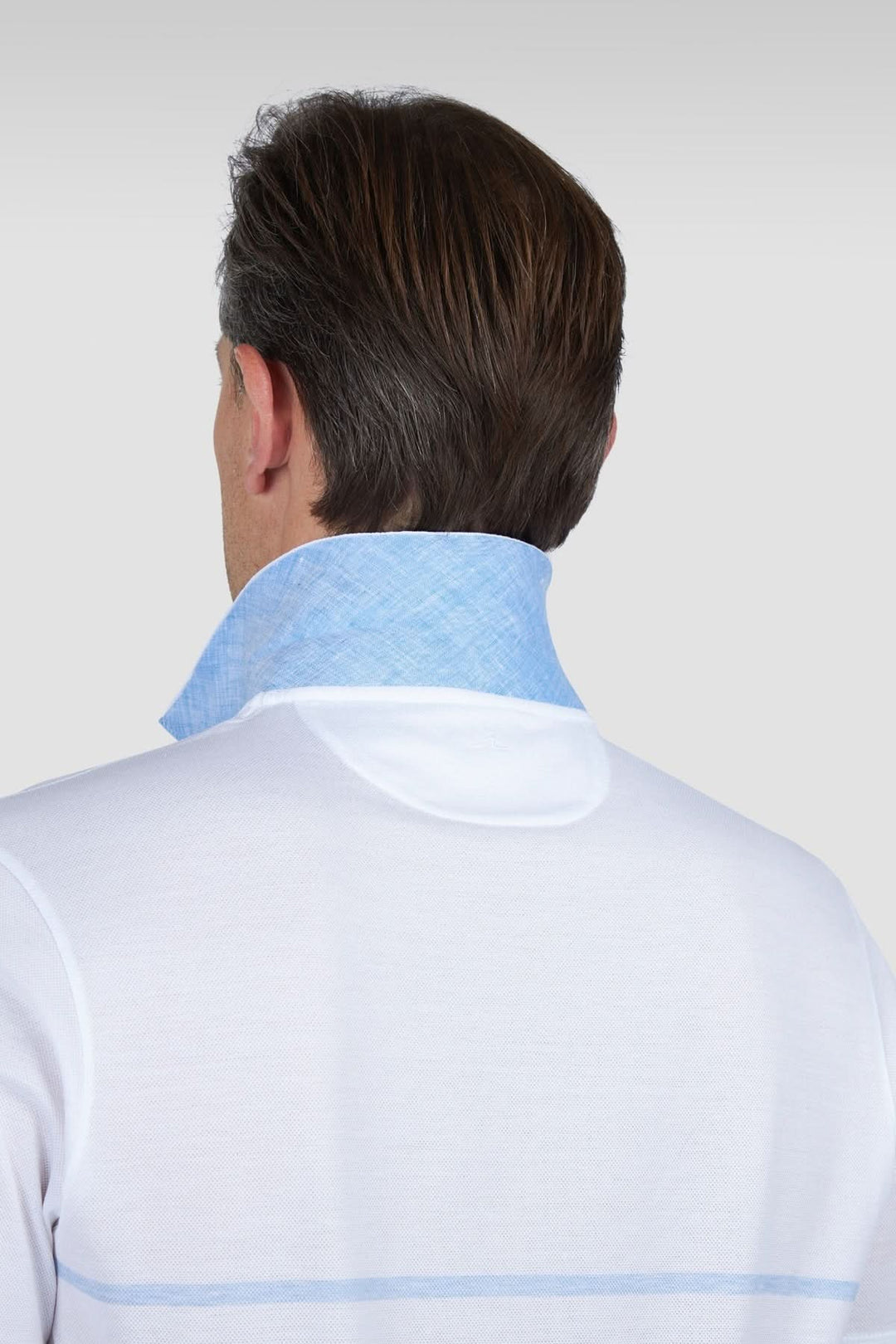 Polo en coton piqué blanc avec col en chambray bleu, vue de l'arrière mettant en valeur les détails de finition.
