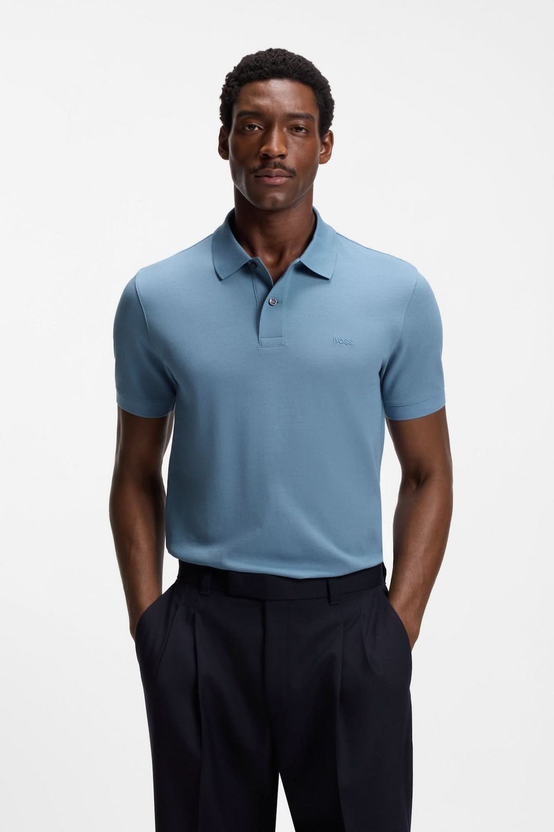 Homme portant un polo en coton piqué à logo brodé bleu avec col polo, manches courtes et coupe droite confortable, idéal pour un look élégant.