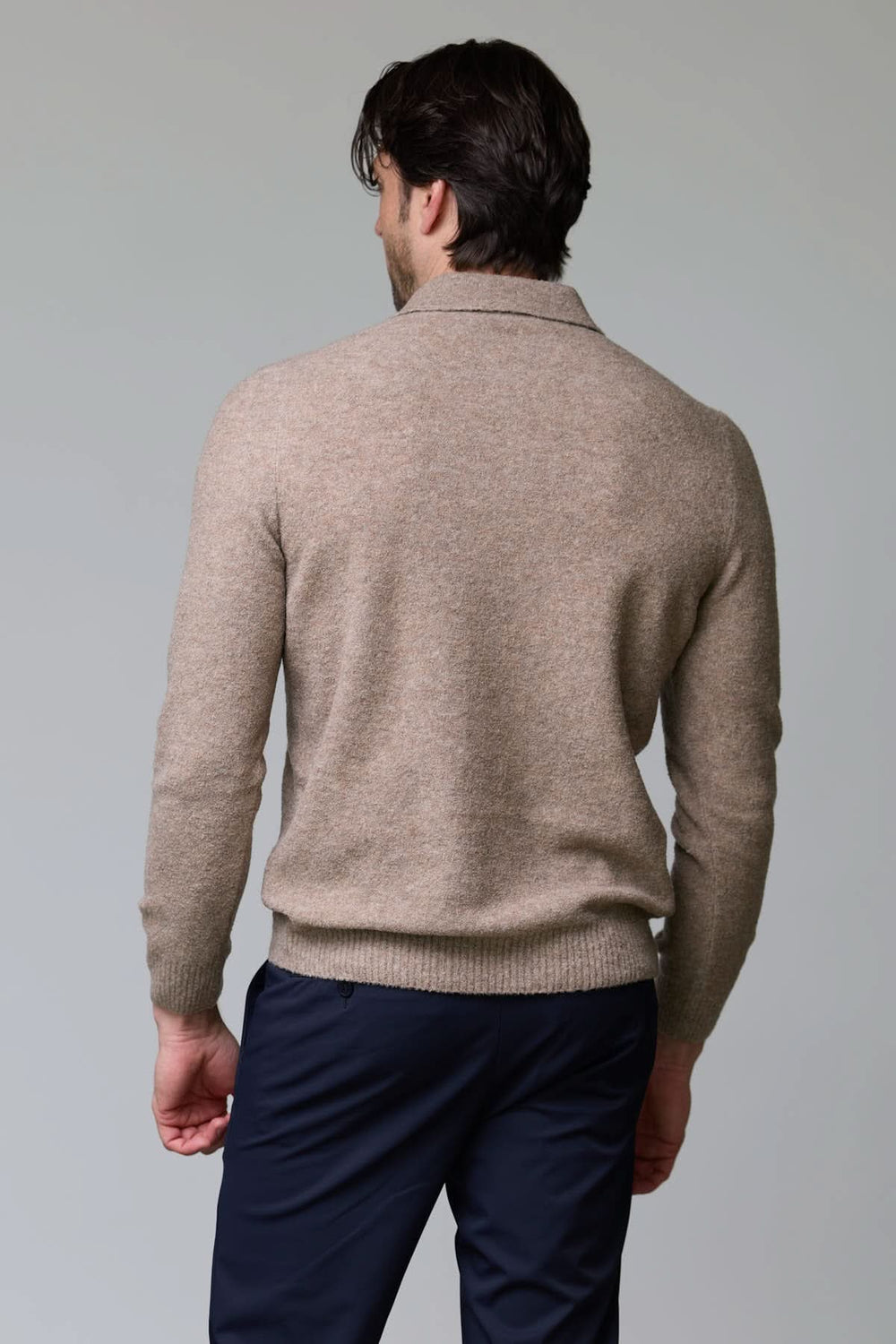Homme dos tourné portant Polo en laine mérinos beige avec col polo et manches longues, coupe élégante et confortable.