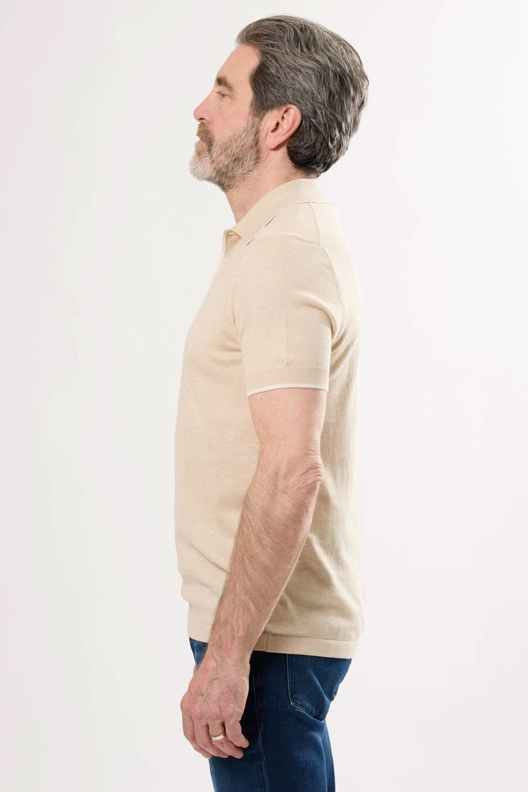 Polo en tricot fin beige porté par un homme, vue de profil, mettant en avant ses manches courtes et son col classique.