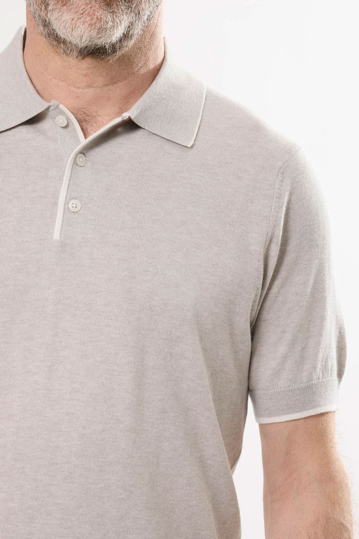 Polo en tricot fin beige avec col classique et manches courtes, parfait pour un style décontracté et élégant.