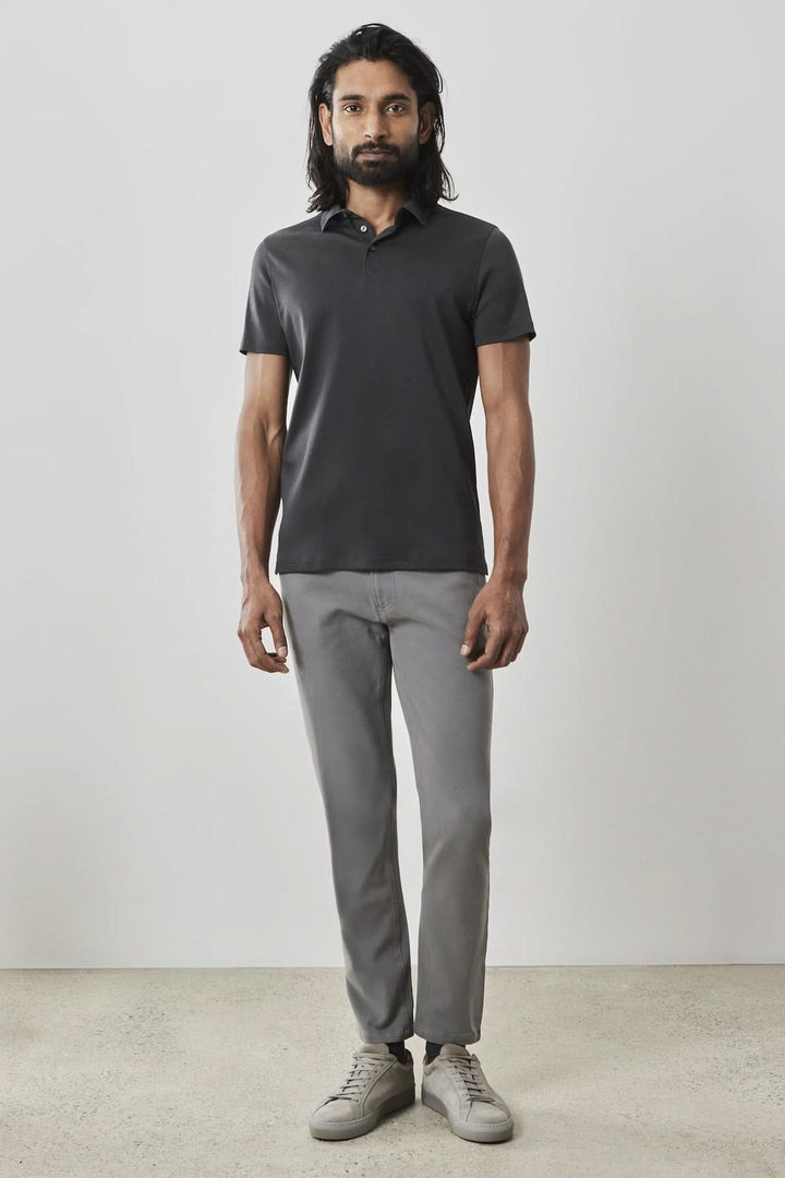 Homme portant un polo manches courtes Georgia en noir avec un pantalon gris, style chic et décontracté.