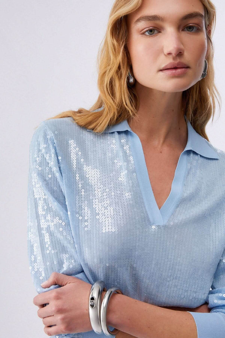 Femme portant un Polo à manches longues avec paillettes, col ouvert, maille scintillante, style moderne et élégant.