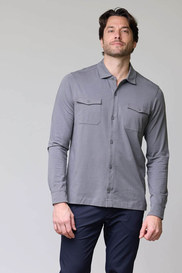 Homme portant un polo à poches boutonnées gris avec manches longues et col chemise, style décontracté chic.