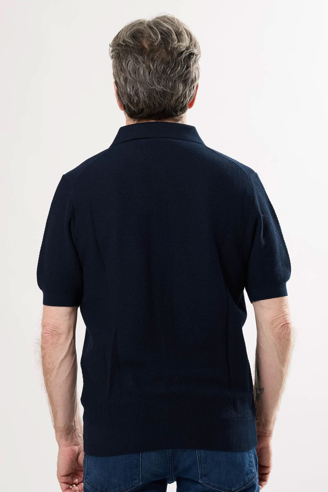 Homme portant un polo raffiné, vue arrière, couleur marine, avec coupe ajustée et col structuré.