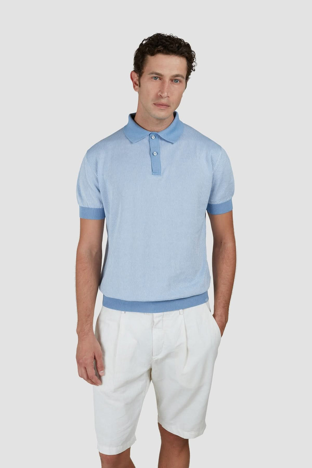 Polo raffiné en maille légère bleu avec short blanc, idéal pour un look estival élégant.