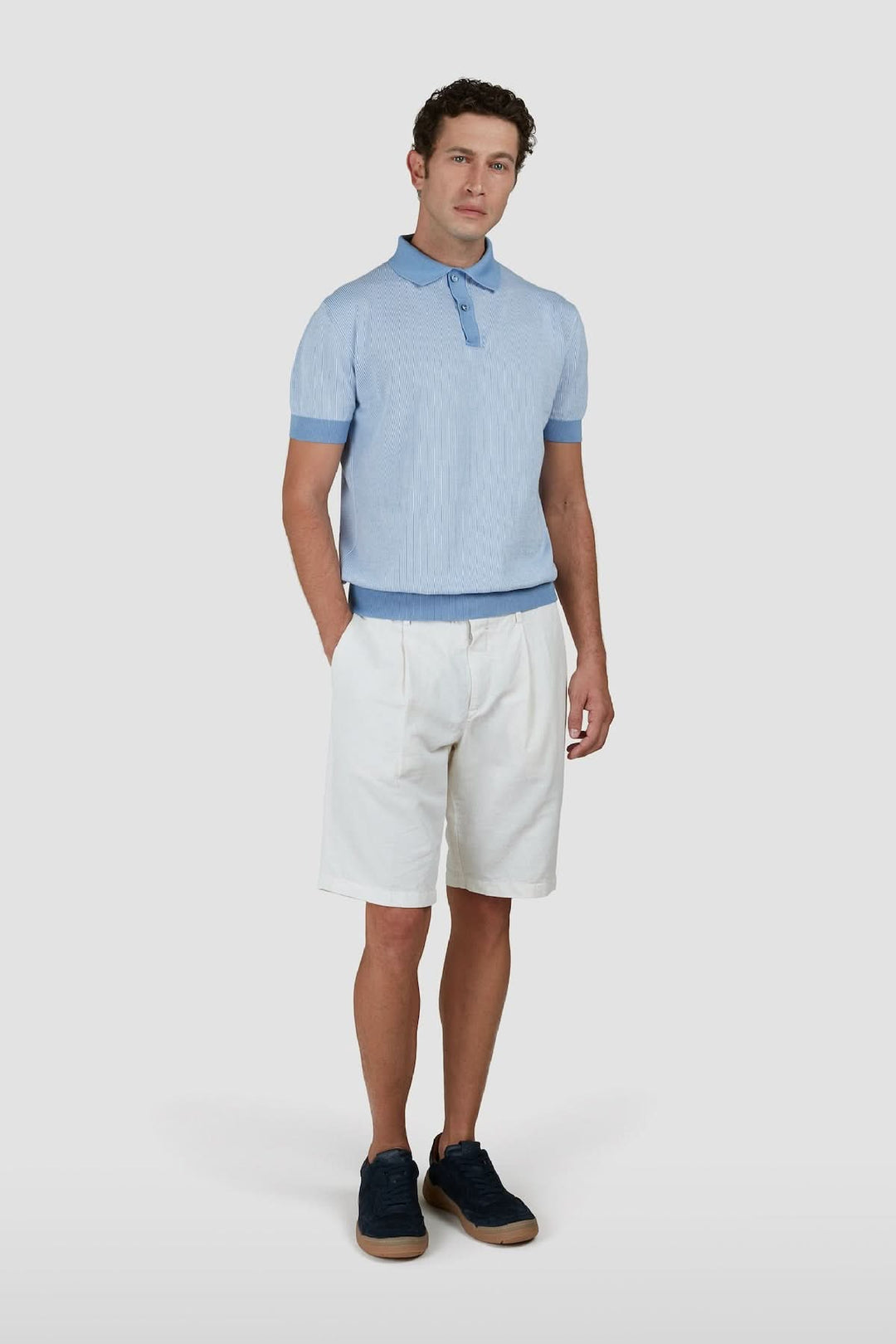 Homme en polo raffiné bleu clair avec short blanc, look élégant et décontracté.