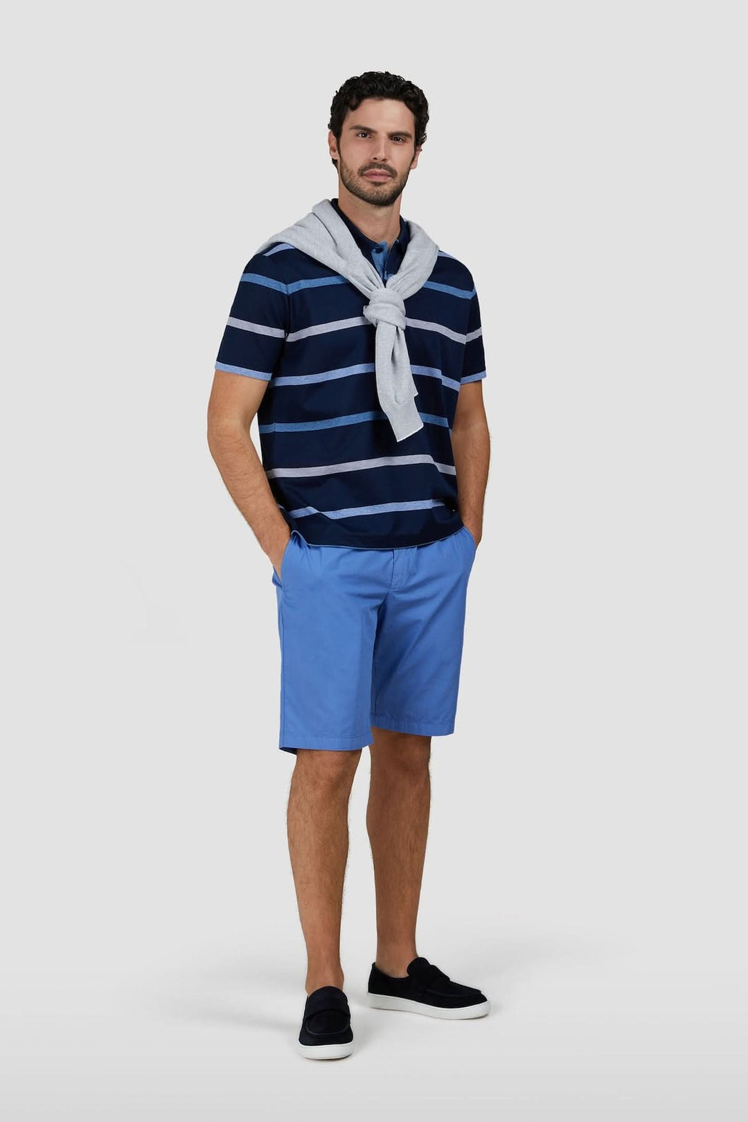 Homme portant un polo rayé en coton piqué, motif à rayures horizontales, style estival élégant.