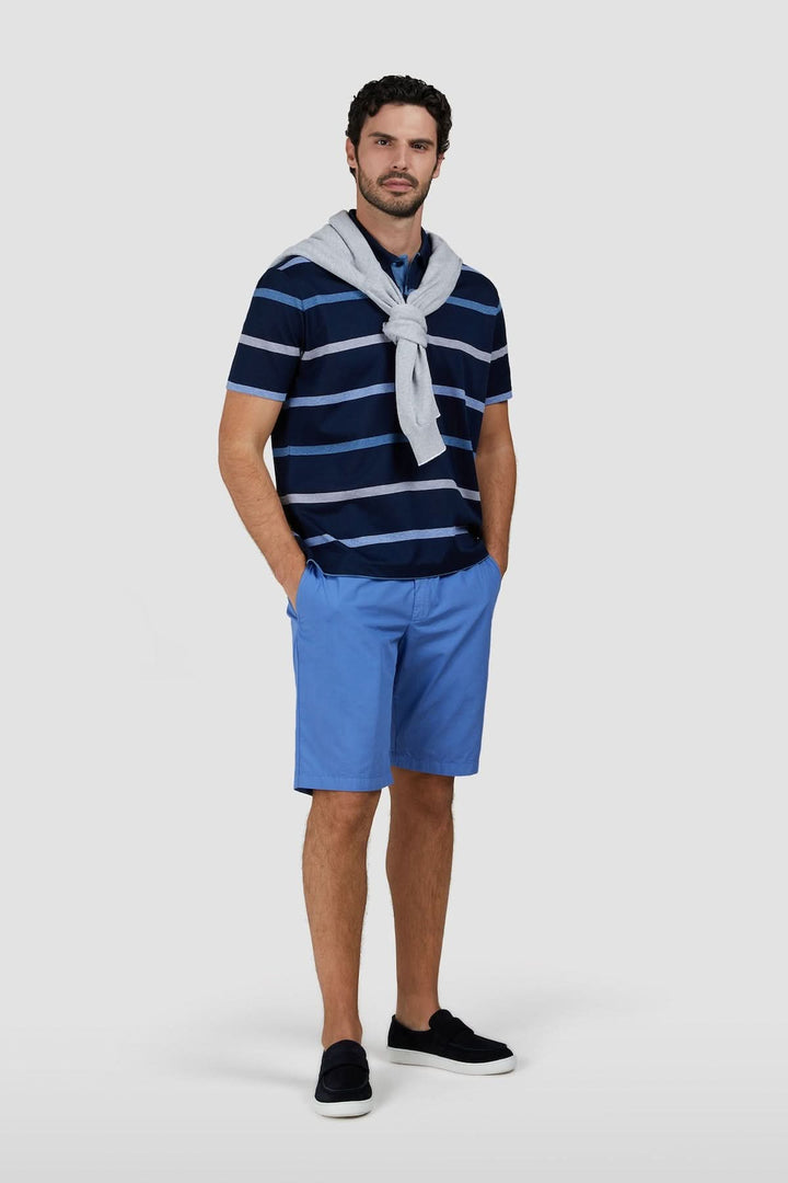 Homme portant un polo rayé en coton piqué, motif à rayures horizontales, style estival élégant.