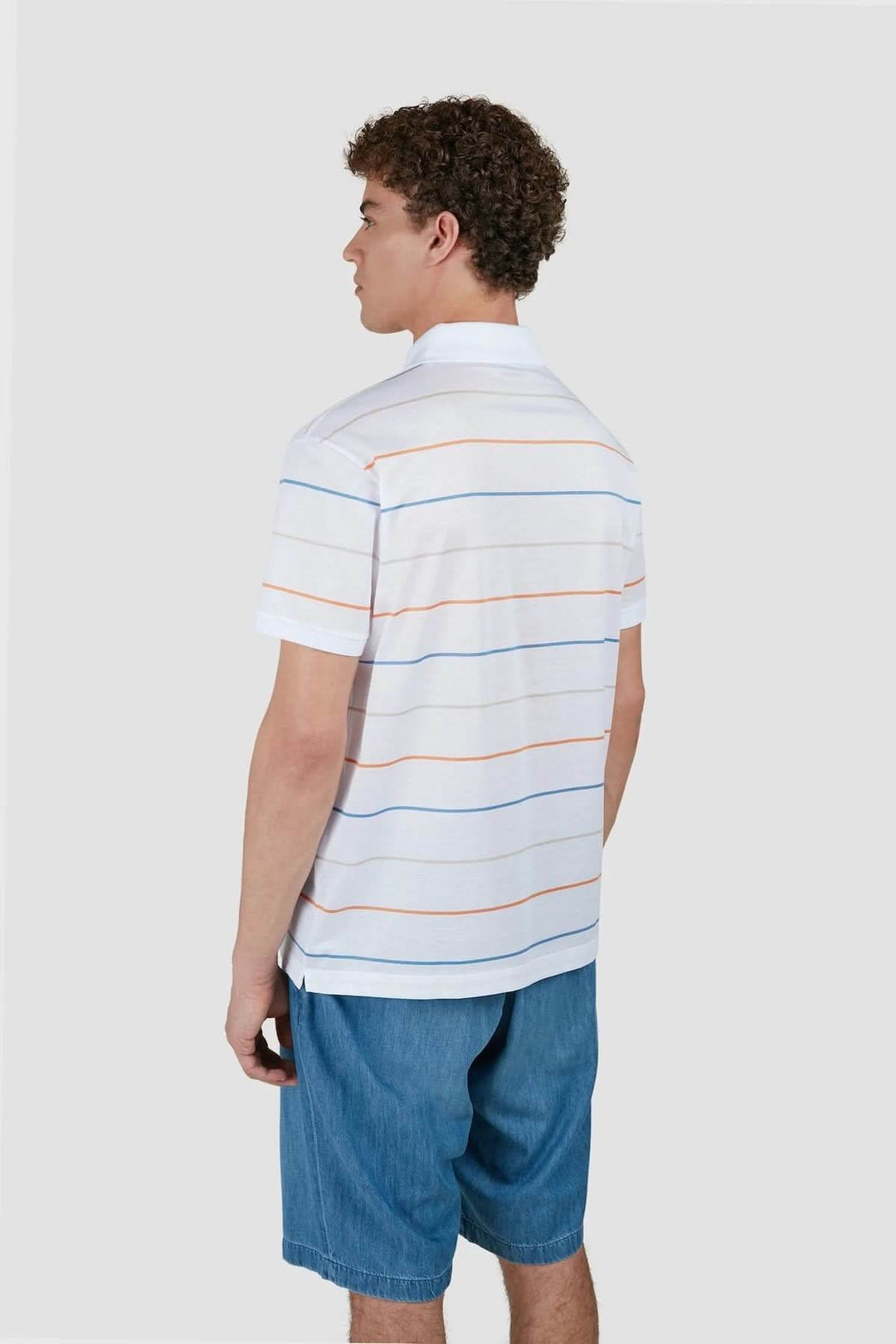 Homme vue de dos portant un polo à rayures multicolores avec un short en denim, style décontracté.