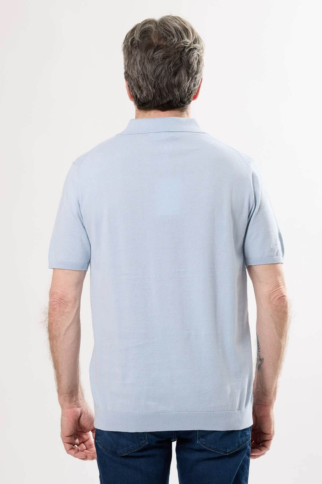 Homme portant un polo rétro léger vu de dos, couleur bleu clair, avec coupe élégante et manches courtes.