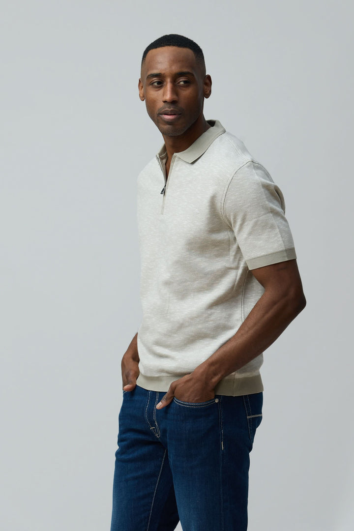 Homme portant un polo texturé à fermeture zippée, style décontracté et élégant, coupe régulière en coton peigné et flammé.