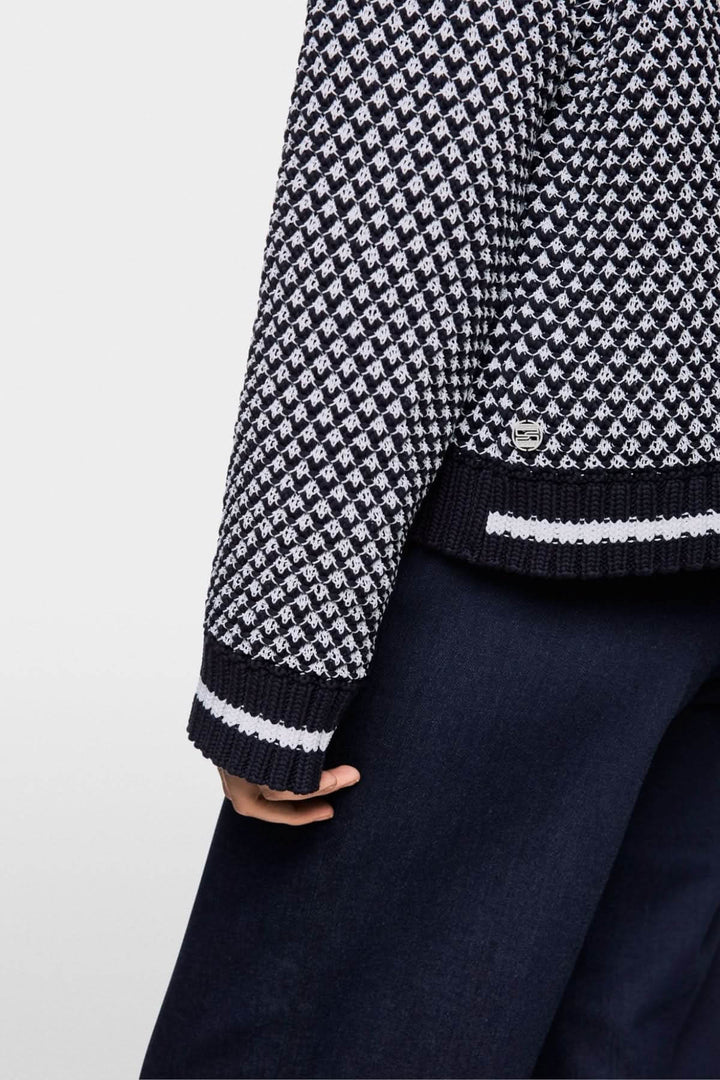 Chandail court tricoté en noir et blanc avec motif texturé, porté sur un pantalon fluide.