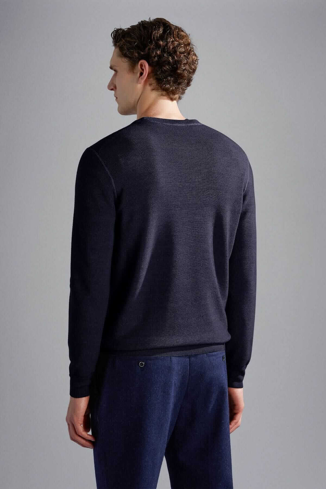 Homme portant un pull en laine mérinos marine vu de dos, style élégant et sobre.