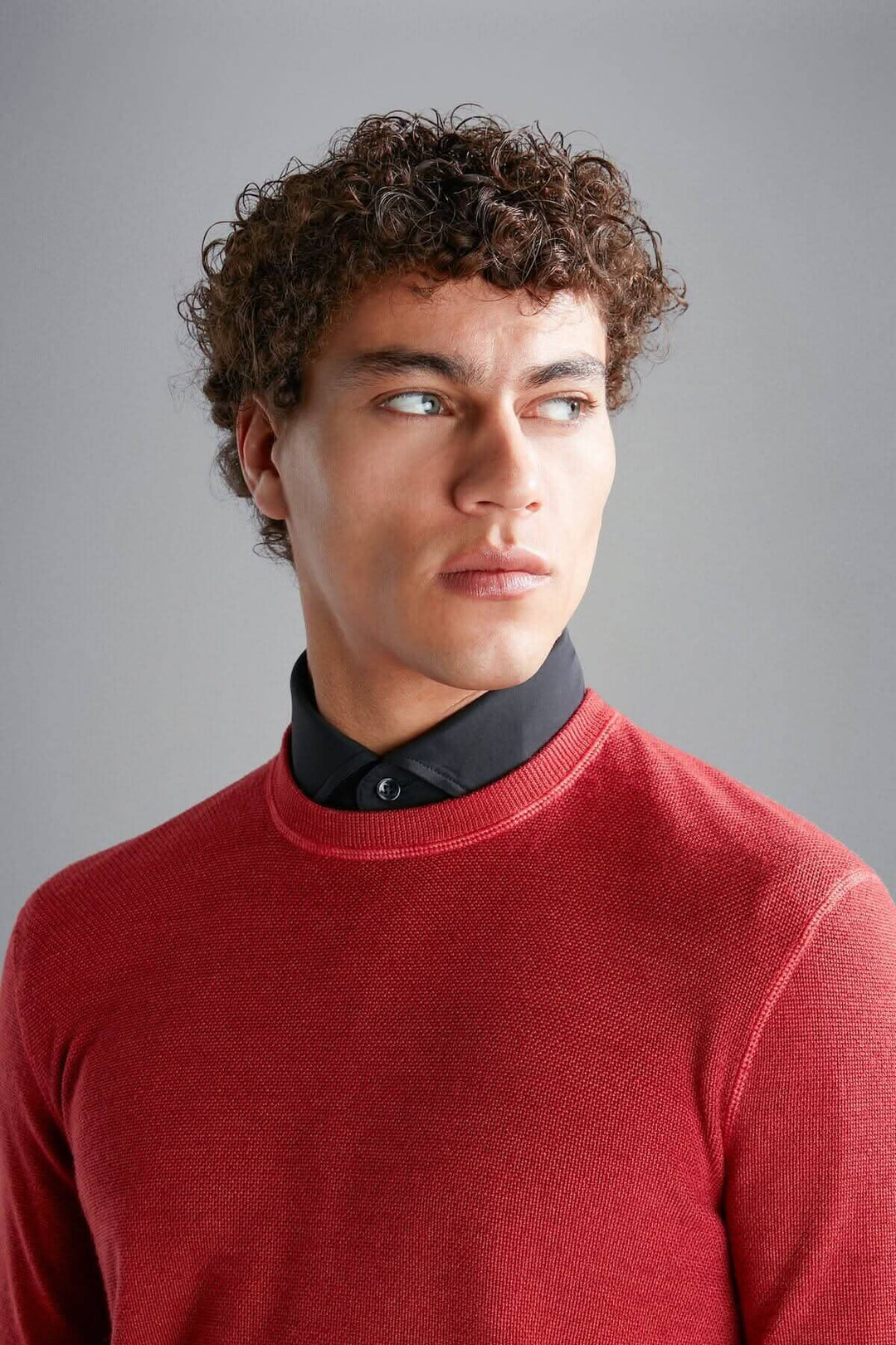 Pull en laine mérinos rouge avec col rond classique porté par un homme au style moderne.