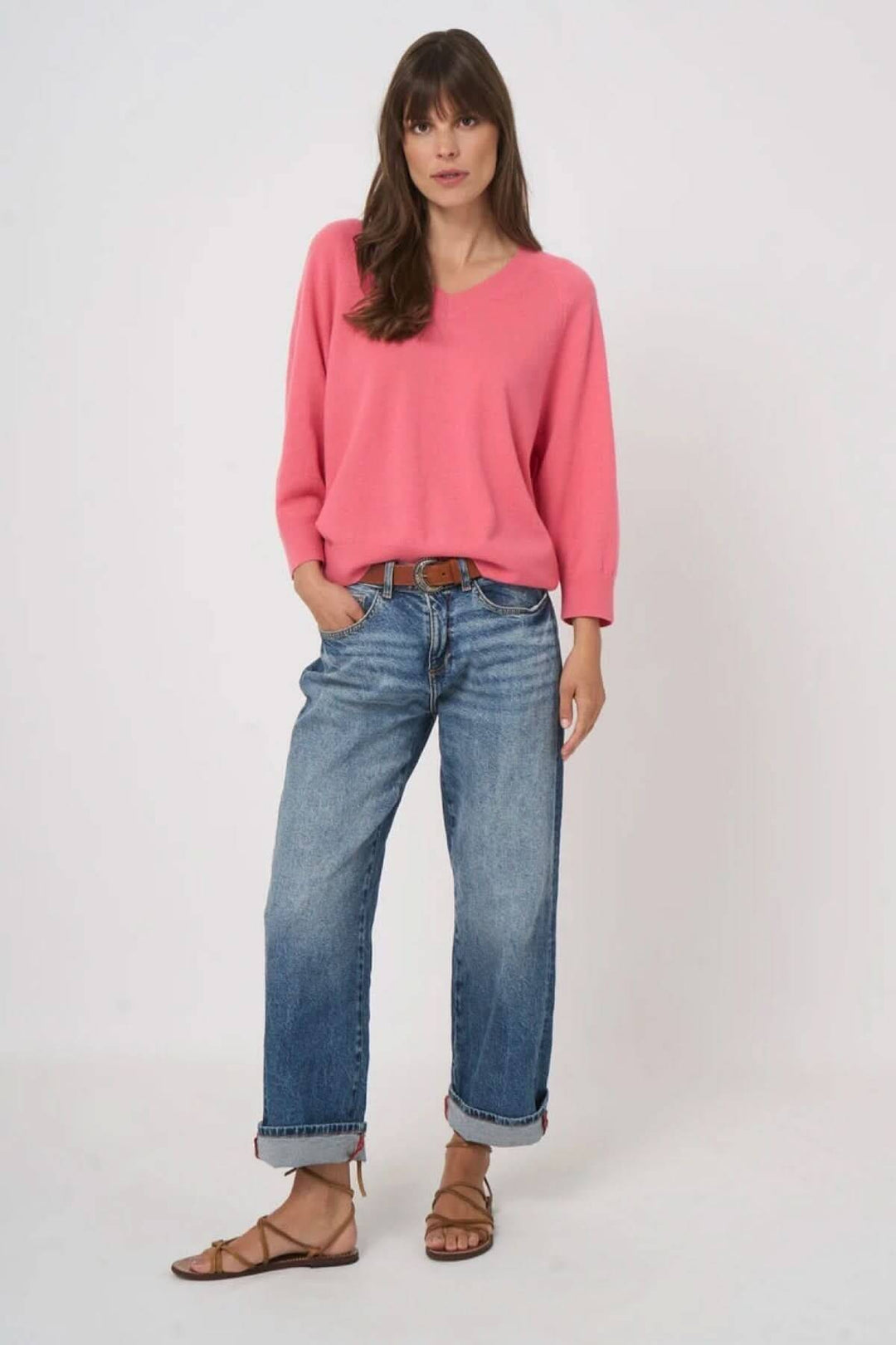 Femme portant un pull en tricot à col en V rose avec jeans décontractés.