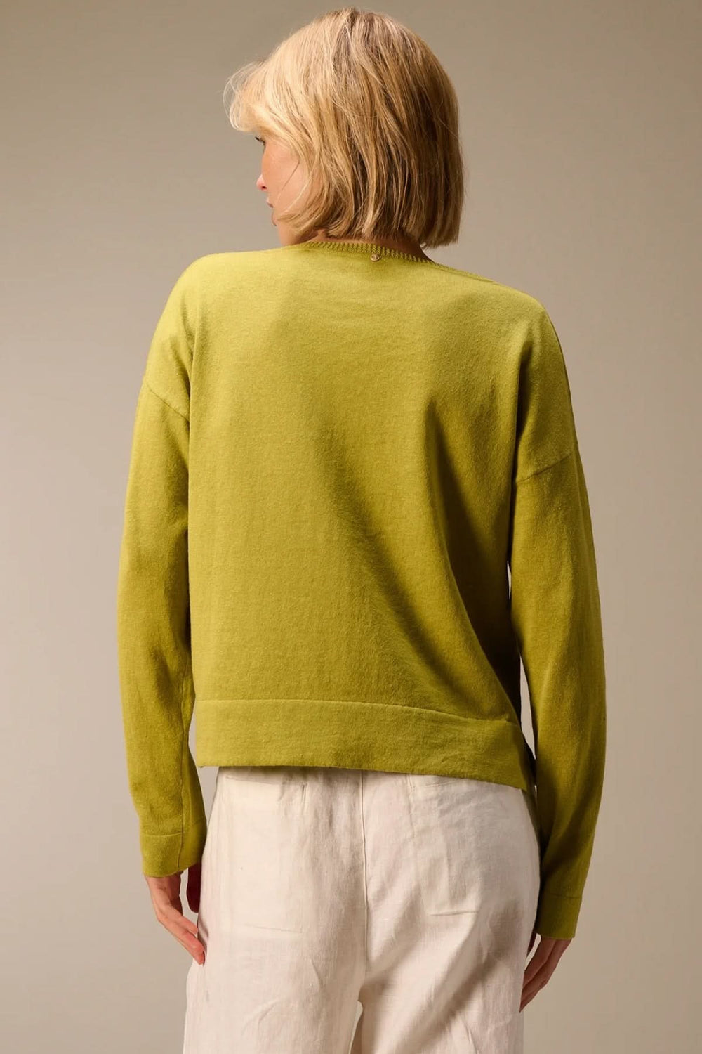 Dos d'un pull léger manches longues en maille douce et fluide, idéal pour superposer, montré sur une femme de dos, couleur vert clair.