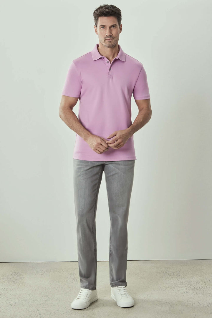 Homme portant un polo manches courtes rose Georgia avec pantalon gris et chaussures blanches.