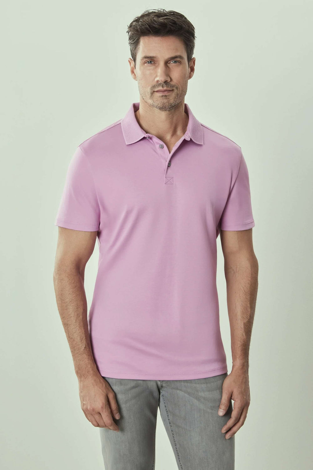 Homme portant un polo manches courtes Georgia en couleur rose, col de chemise et patte de boutonnage.