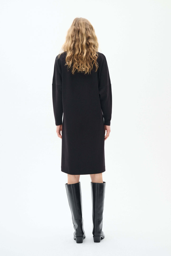 Vue arrière de la robe Annie à manches longues, couleur noire, avec des bottes hautes élégantes.