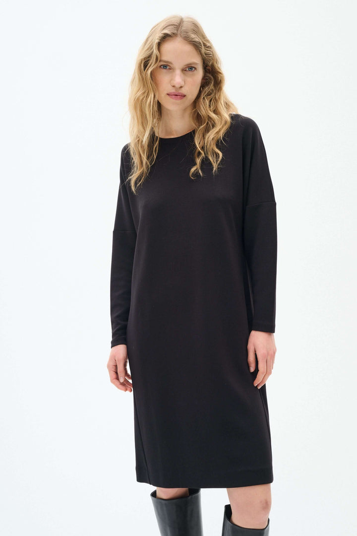 Robe Annie noire à manches longues avec coupe minimaliste et silhouette fluide, parfaite pour un look décontracté ou sophistiqué.