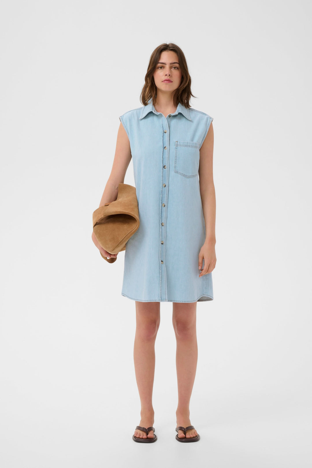 Femme portant une robe Elly chemise sans manches en jean avec un sac, coupe droite décontractée. Description du produit en français.