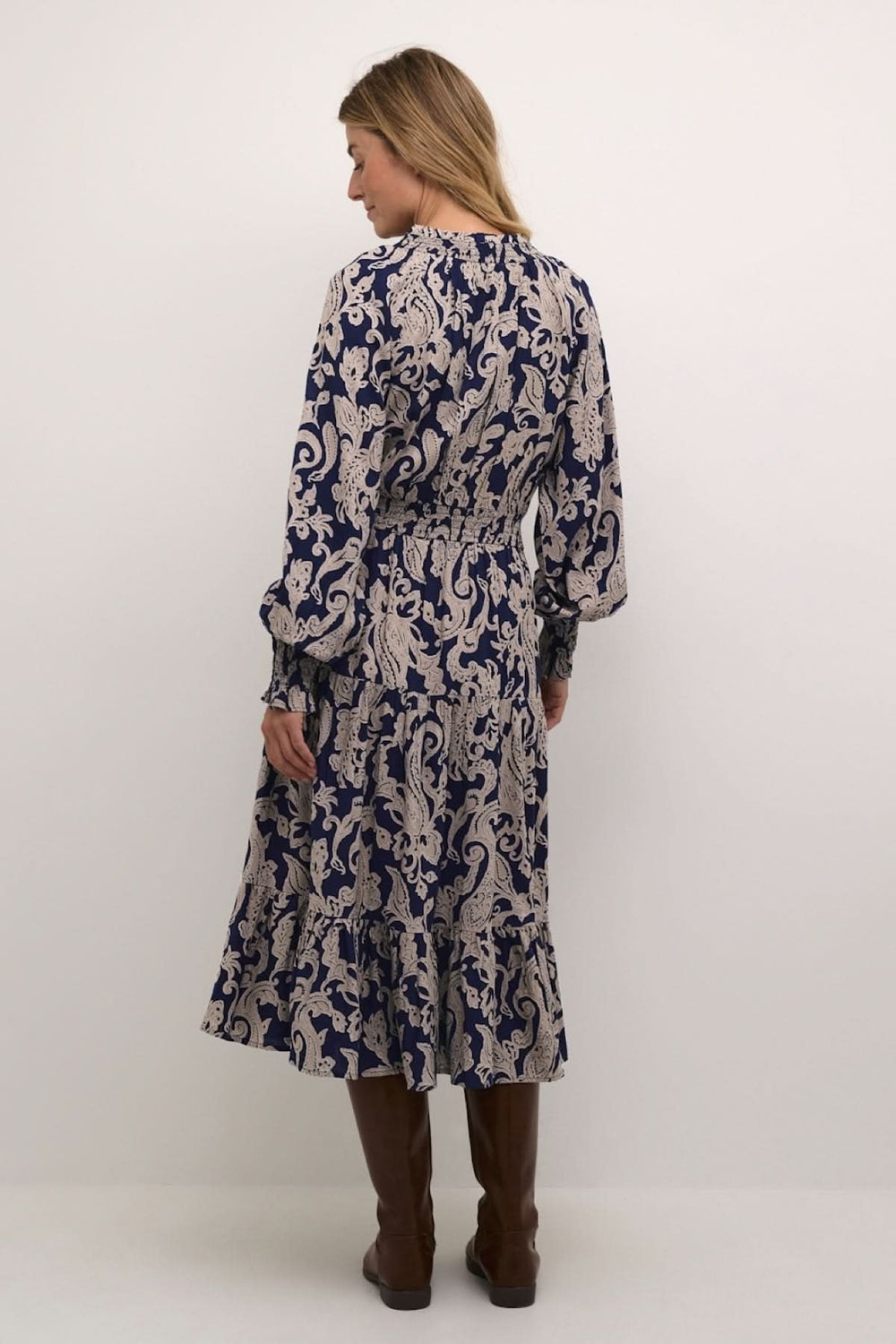 Robe Lucy longue en motif beige sur fond bleu marine, vue arrière, avec manches longues et ceinture à la taille.