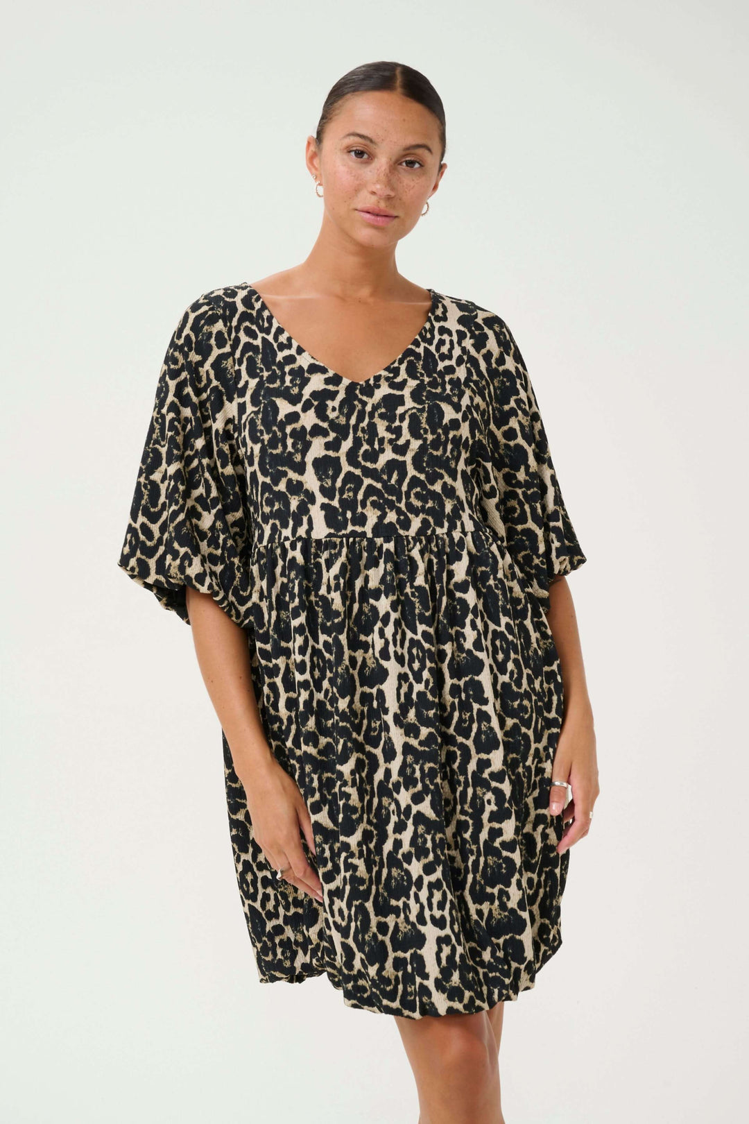 Robe Nani à imprimé léopard, courte avec encolure en V et manches amples, offrant un style moderne et audacieux.