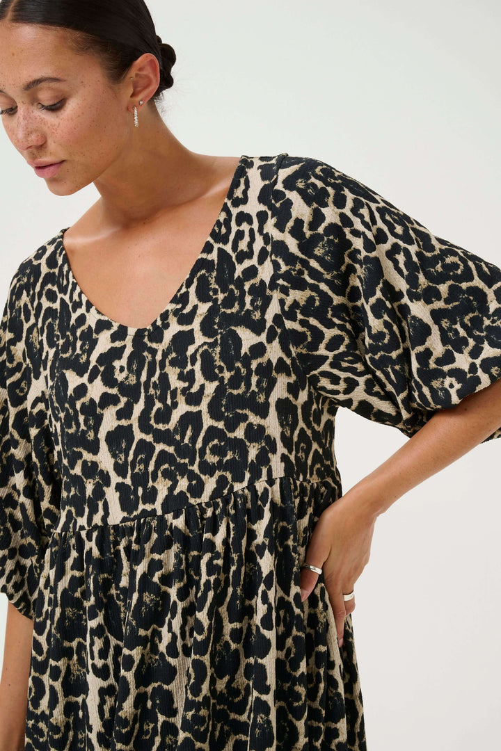 Robe courte à imprimé léopard avec encolure en V et manches amples pour un look moderne et audacieux.