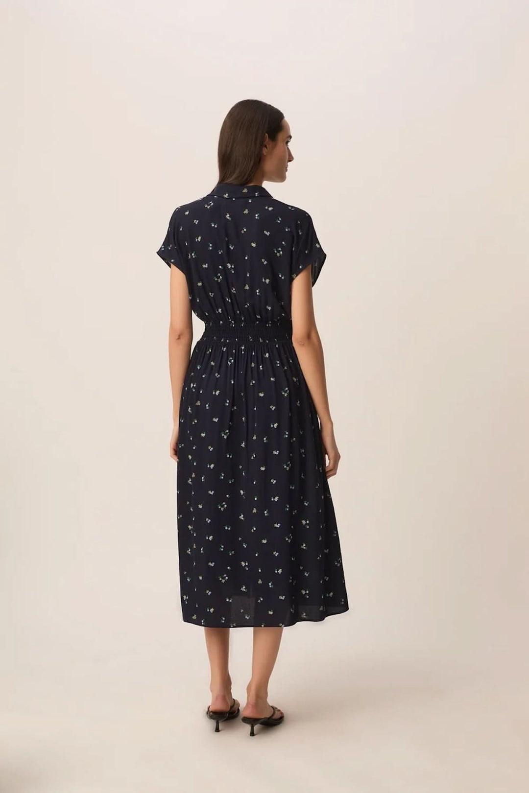 Femme portant une Robe Renaldi midi fluide à taille smockée, vue de dos, avec manches courtes et encolure en V.