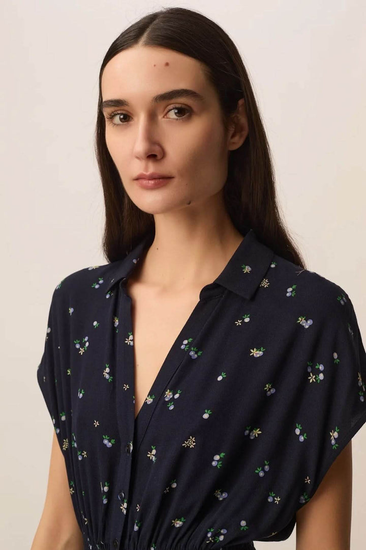 Modèle portant la Robe Renaldi midi fluide à taille smockée avec imprimé floral et encolure en V, élégante et féminine.