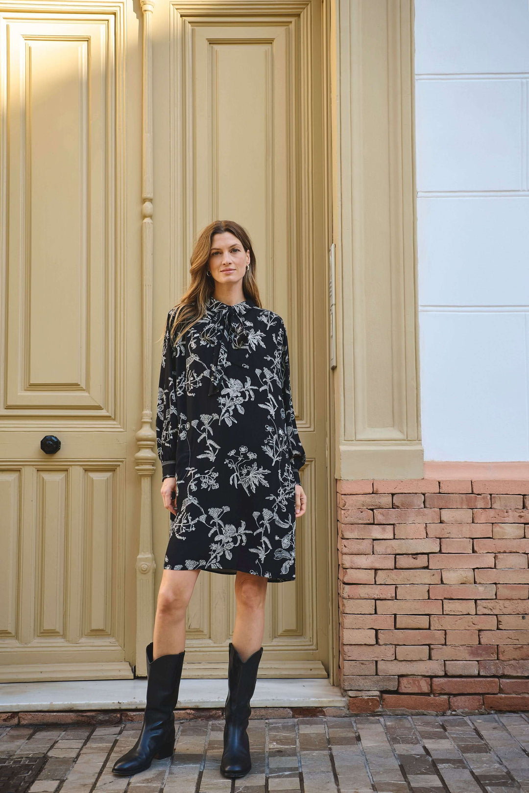 Robe Sanes à imprimé floral, col lavallière, manches bouffantes, portée avec bottes, look chic.