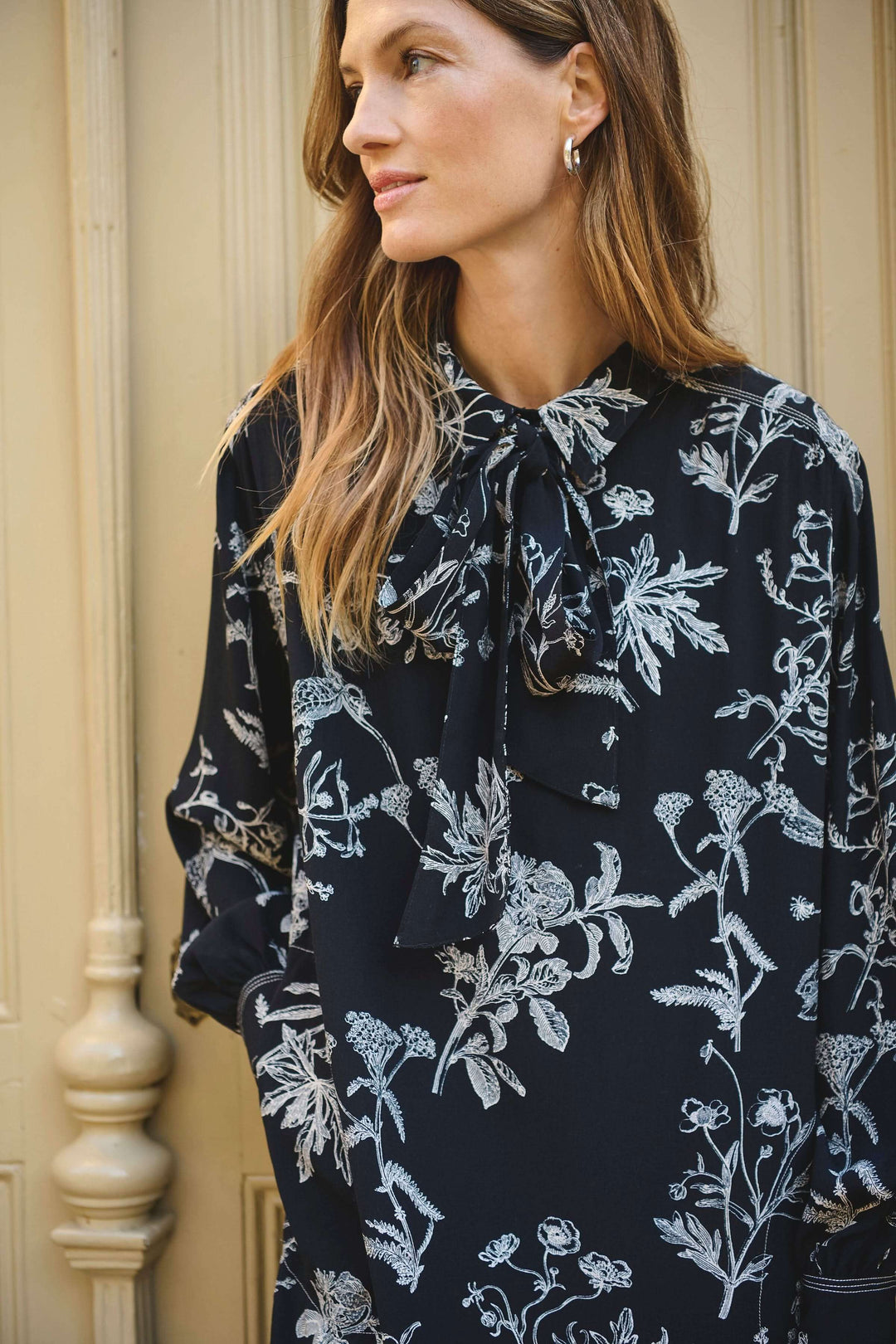 Robe fluide à imprimé floral avec col lavallière et manches longues, parfaite pour un look chic et féminin.