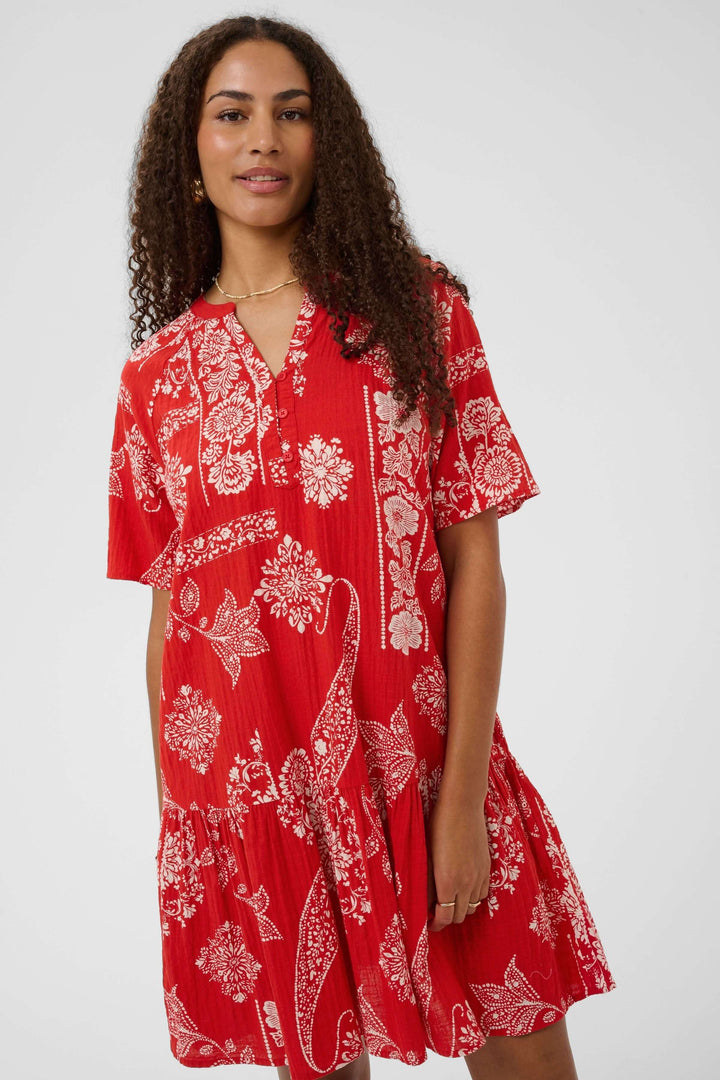 Femme portant une Robe Tiah courte imprimée à manches courtes avec volant et tissu léger, idéale pour l&