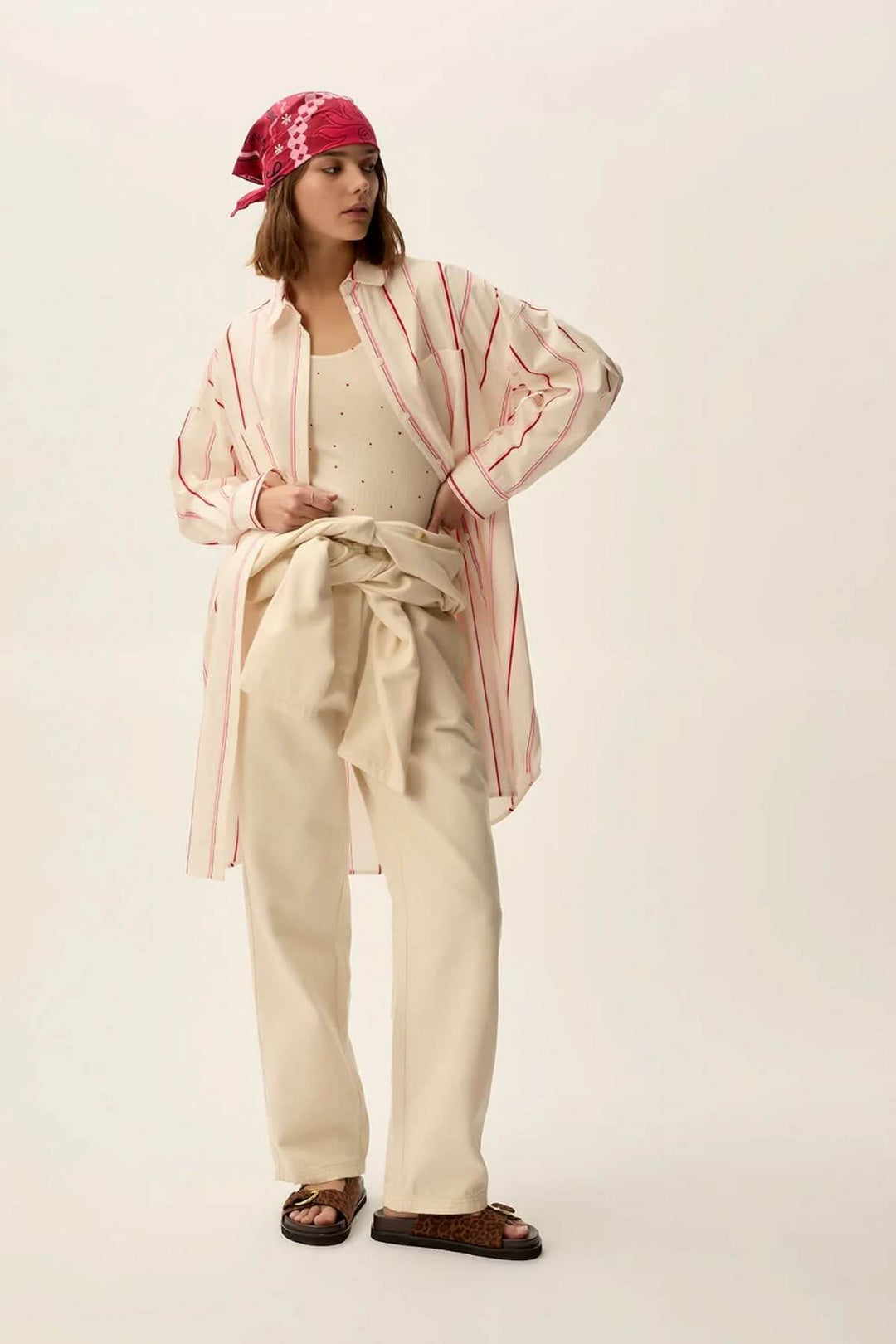 Modèle portant une robe longue rayée rose, tenue oversize avec un pantalon clair et bandeau coloré.