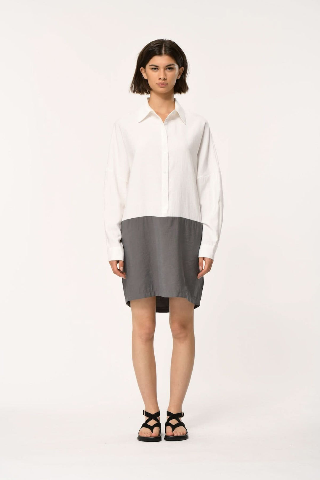 Femme portant une robe chemise bimatière à coupe droite, contraste moderne et structuré, idéale pour bureau et décontracté.