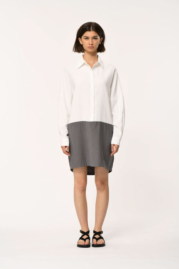 Femme portant une robe chemise bimatière à coupe droite, contraste moderne et structuré, idéale pour bureau et décontracté.