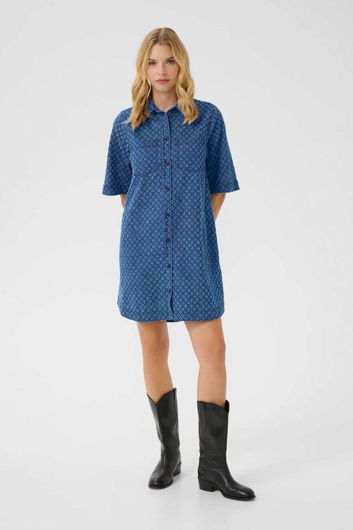 Robe-chemise en denim léger avec motifs géométriques, manches courtes et col classique, portée avec des bottes noires.