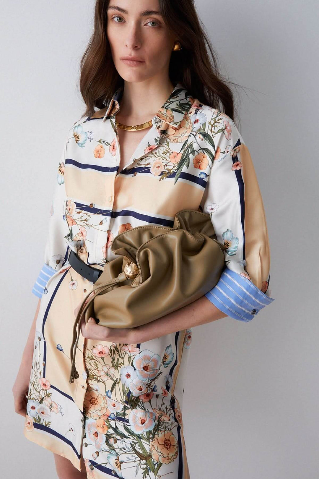 Femme portant une robe chemise à imprimé floral avec col classique et manches trois-quarts, tenue élégante et décontractée.
