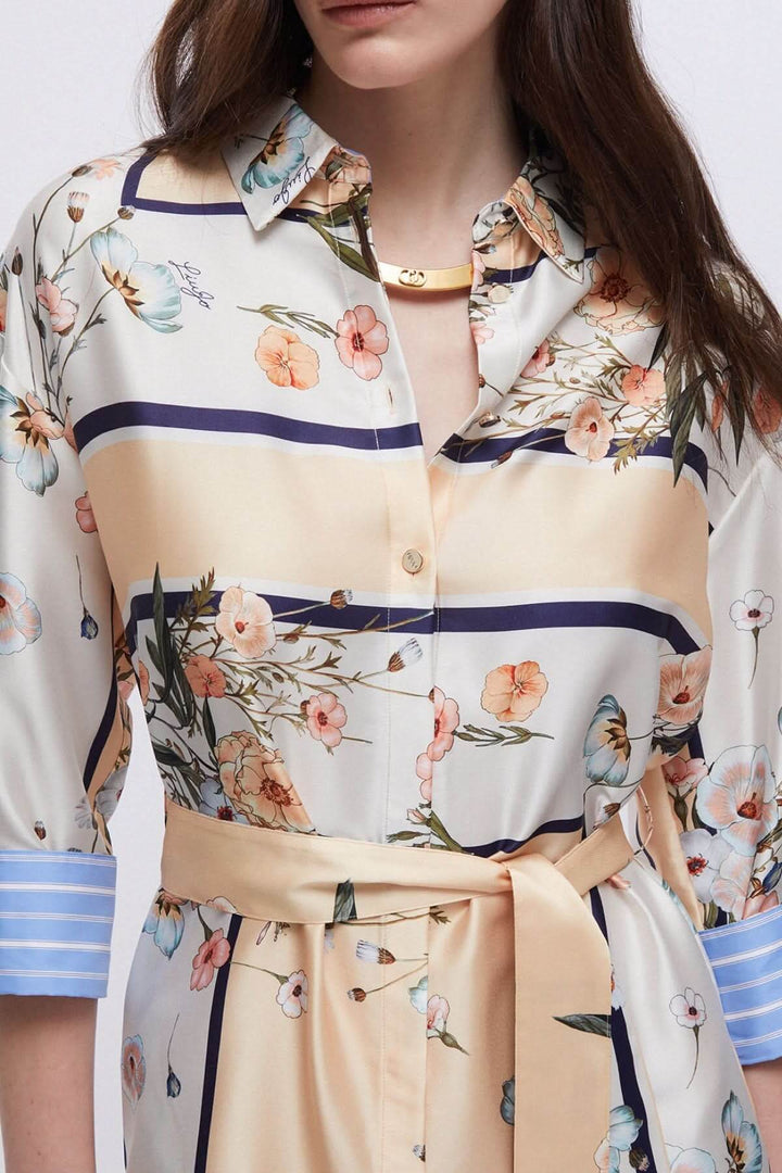 Femme portant une robe chemise à imprimé floral avec col classique et manches trois-quarts.