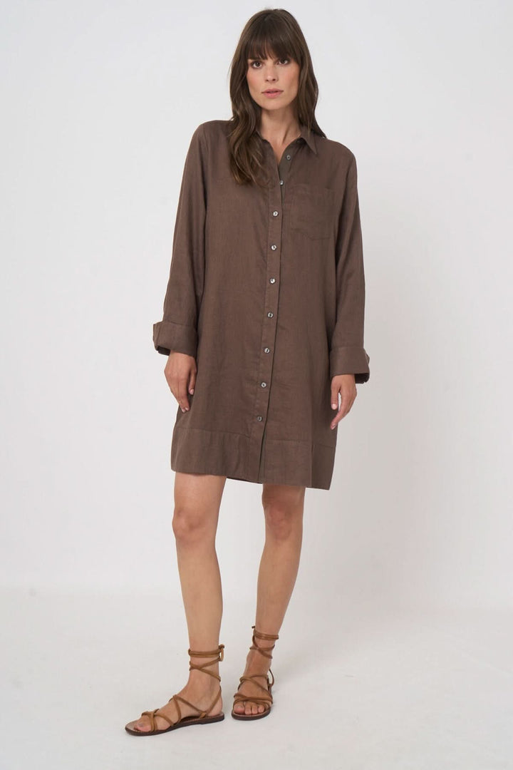 Femme portant une robe chemise à manches longues, coupe ample et fluide, avec des sandales, pour un look estival élégant.