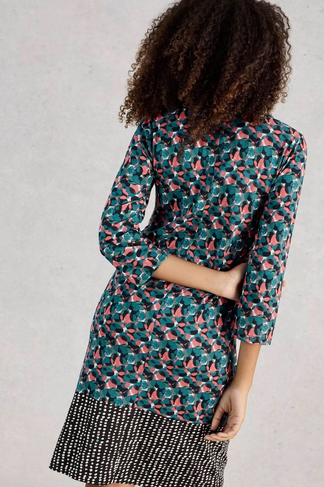 Femme portant une Robe à col V Tallie imprimée graphique, vue de dos, coupe droite pour un look féminin et décontracté.