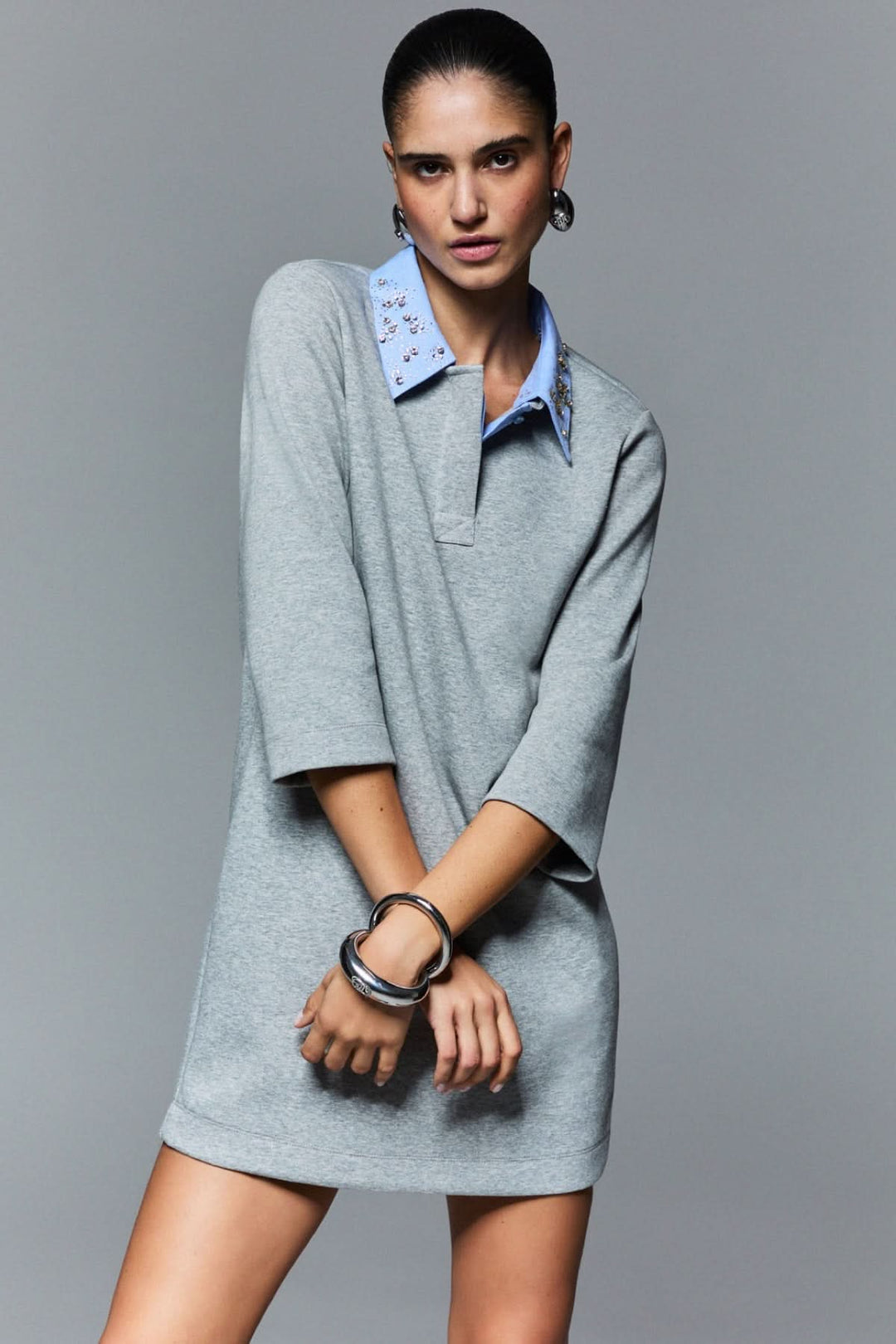 Robe courte à col polo orné avec manches trois-quarts et col décoratif, offrant une allure sport-chic moderne.