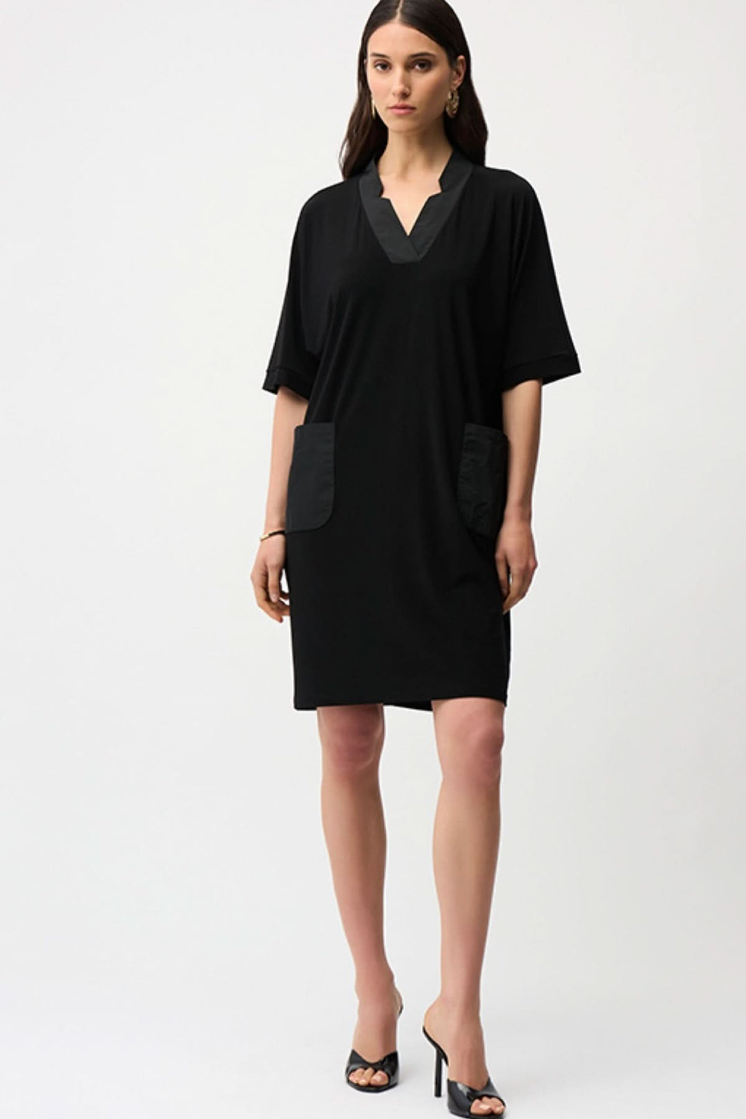 Femme portant une robe droite à col ouvert noire avec poches appliquées et manches courtes, design épuré et moderne.