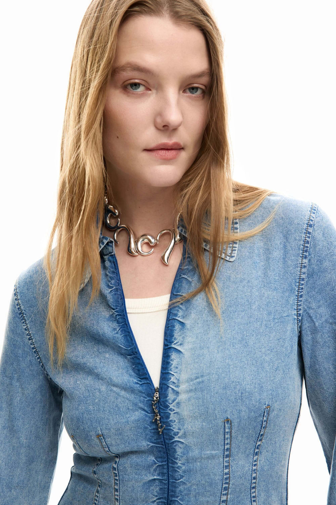 Femme portant une robe en jean slim avec col chemise et découpes verticales pour un look structuré et contemporain.