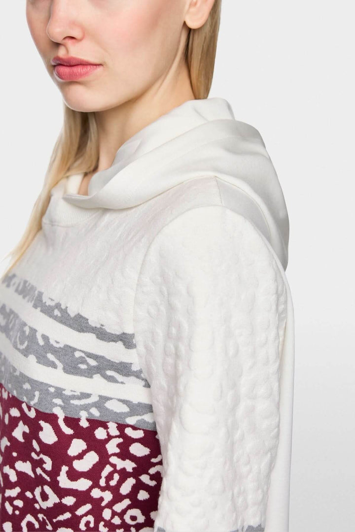 Robe en maille léopard à capuche avec détails tricotés et jersey doux, vue de côté, montrant le motif léopard et la capuche confortable.